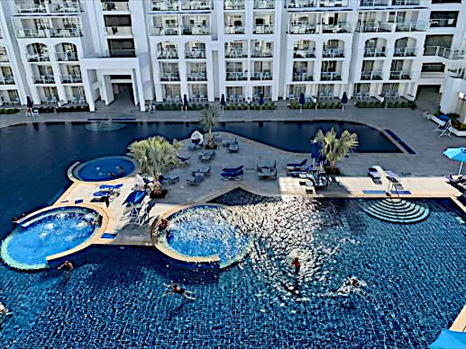 Pool terrace with jacuzzis at Blu Spa Resort seen from above.
