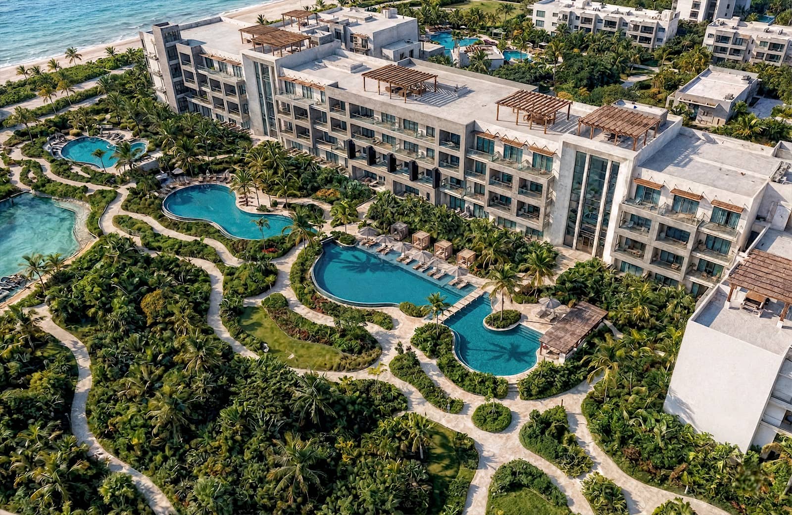 Aerial view of a beachfront resort with lagoon pools and landscaped gardens.