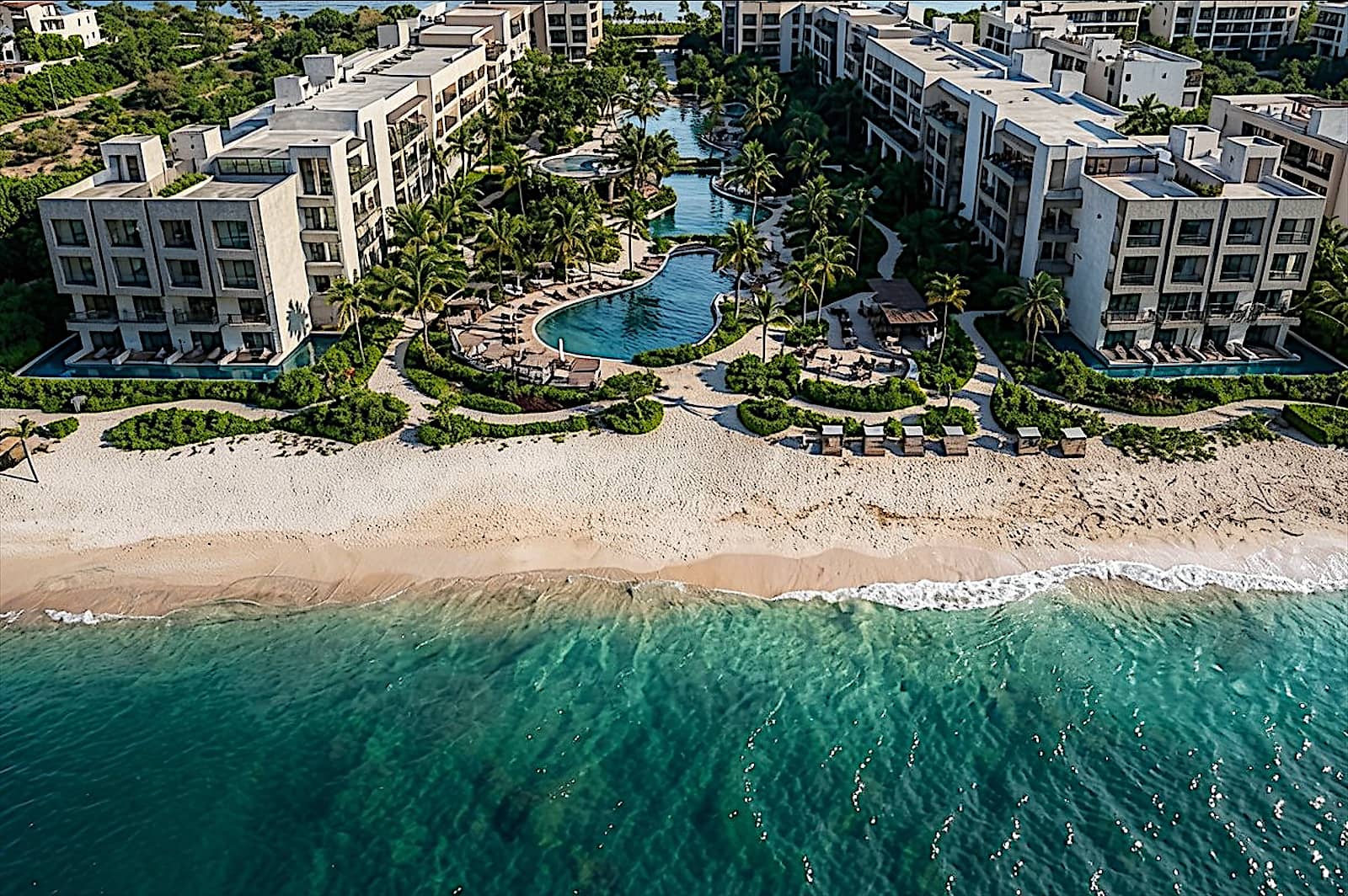 Aerial render of resort blocks and lagoon pools beside the beach.